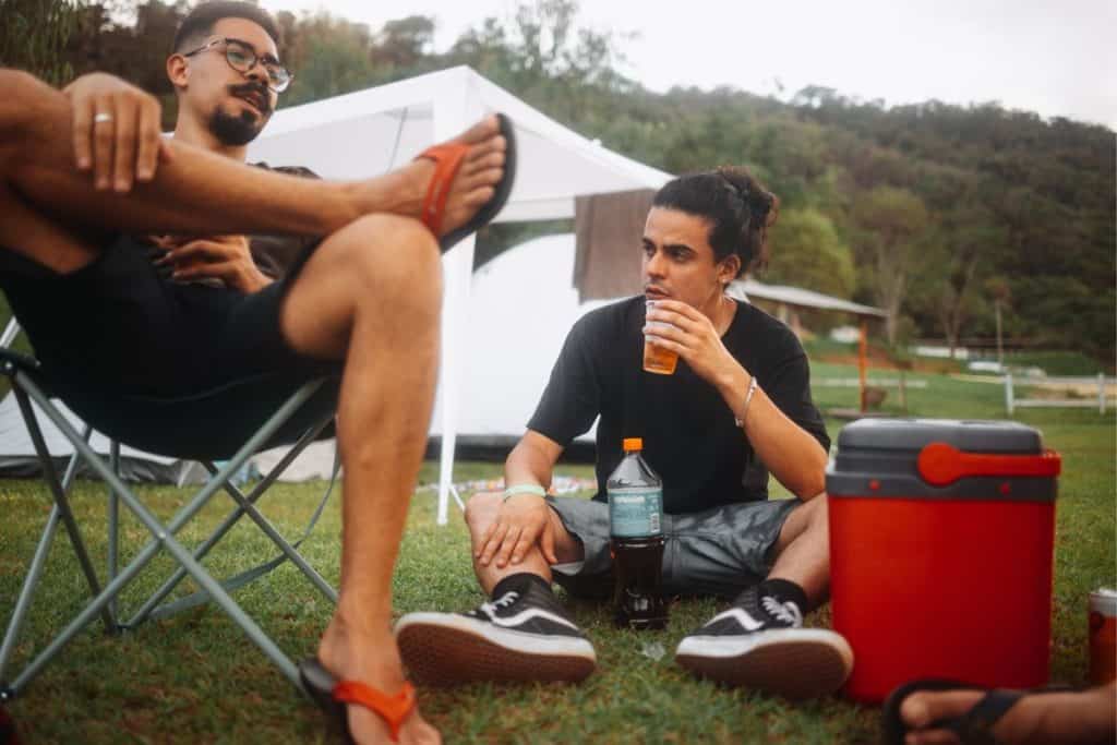 two men sitting by a red cooler