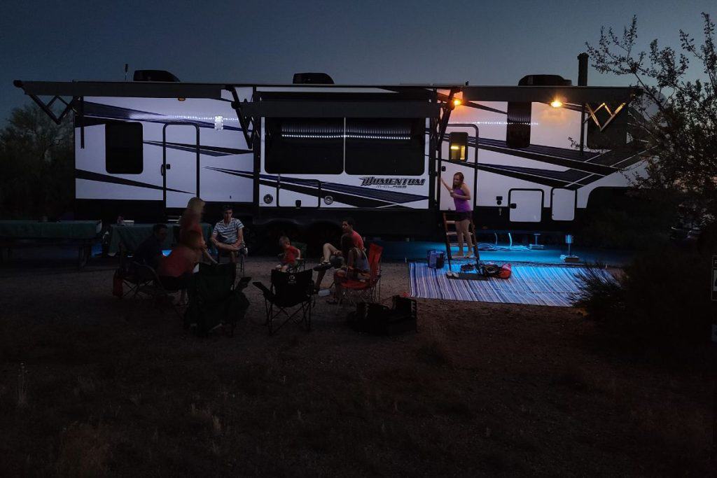 people sitting around an rv at night