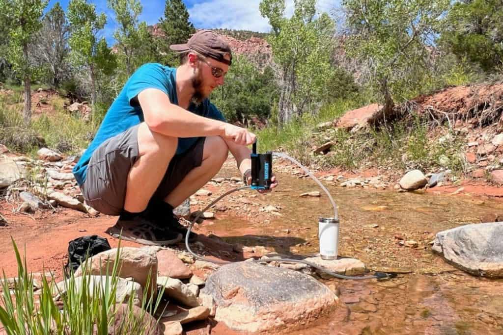 man using a water filter in a stream in utah