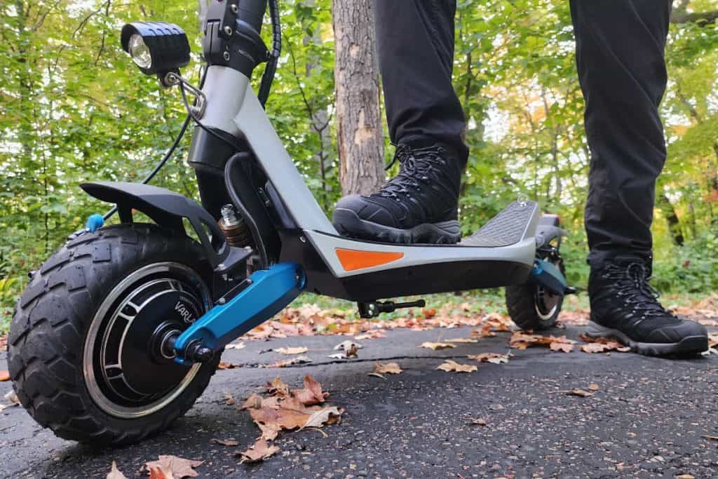 blue scooter on pavement with a man standing on it