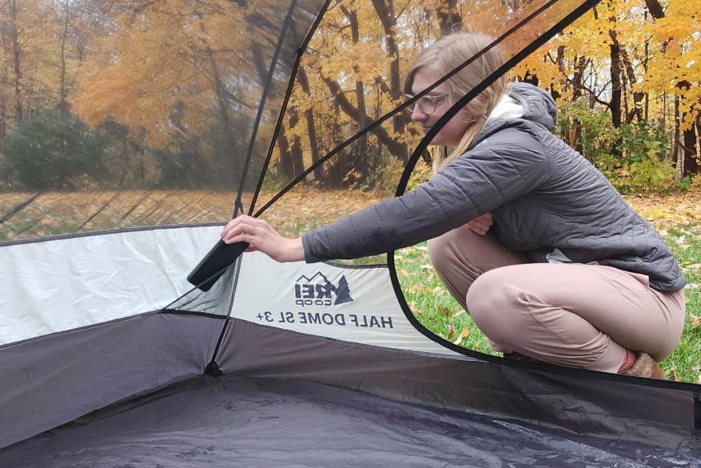 blonde woman putting a phone in a tent pocket