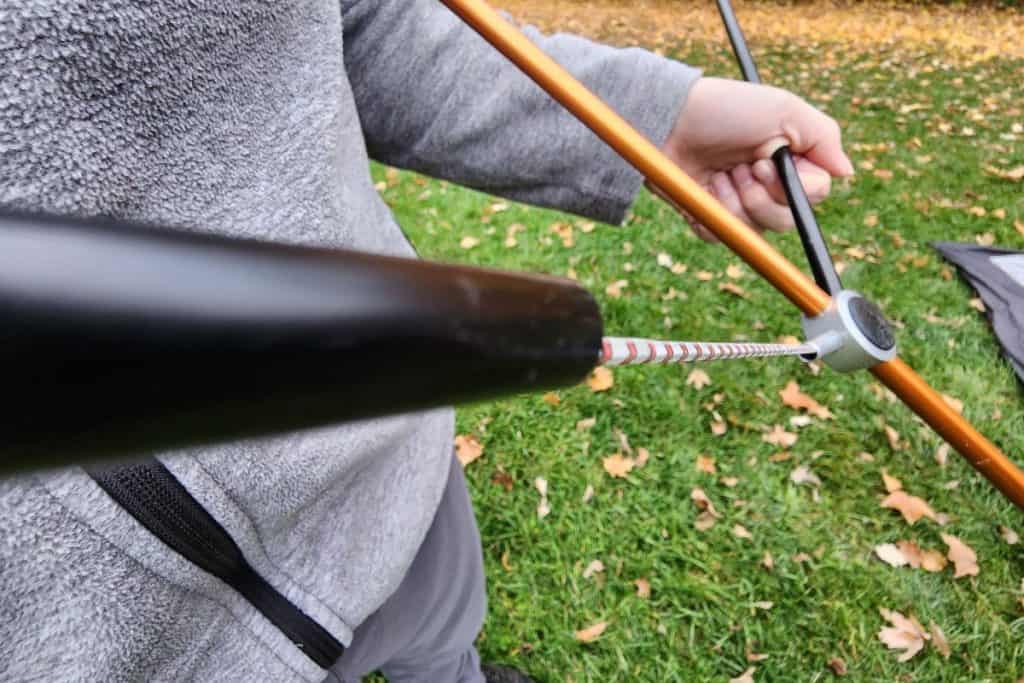 man holding black and orange tent poles